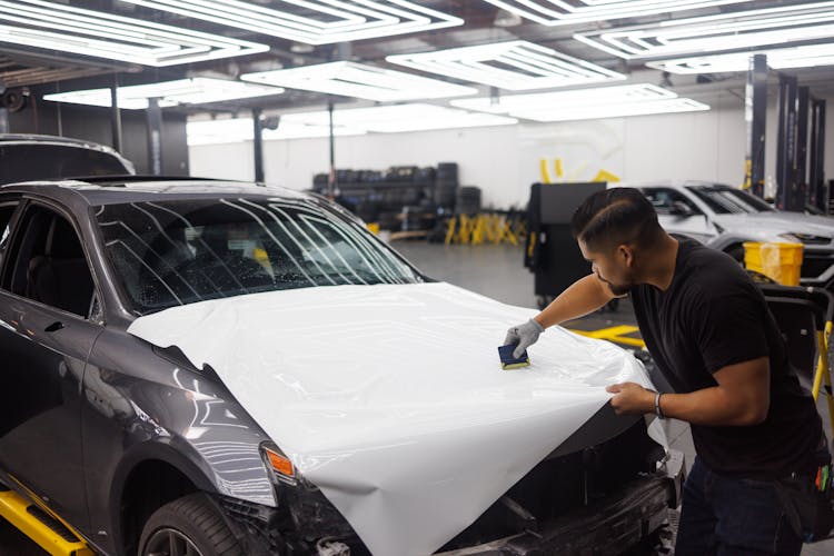 A Man Wrapping A Car Hood