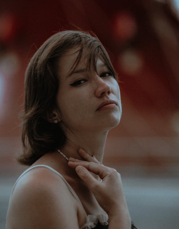 A Woman in White Tank Top with Her Hand on Her Neck