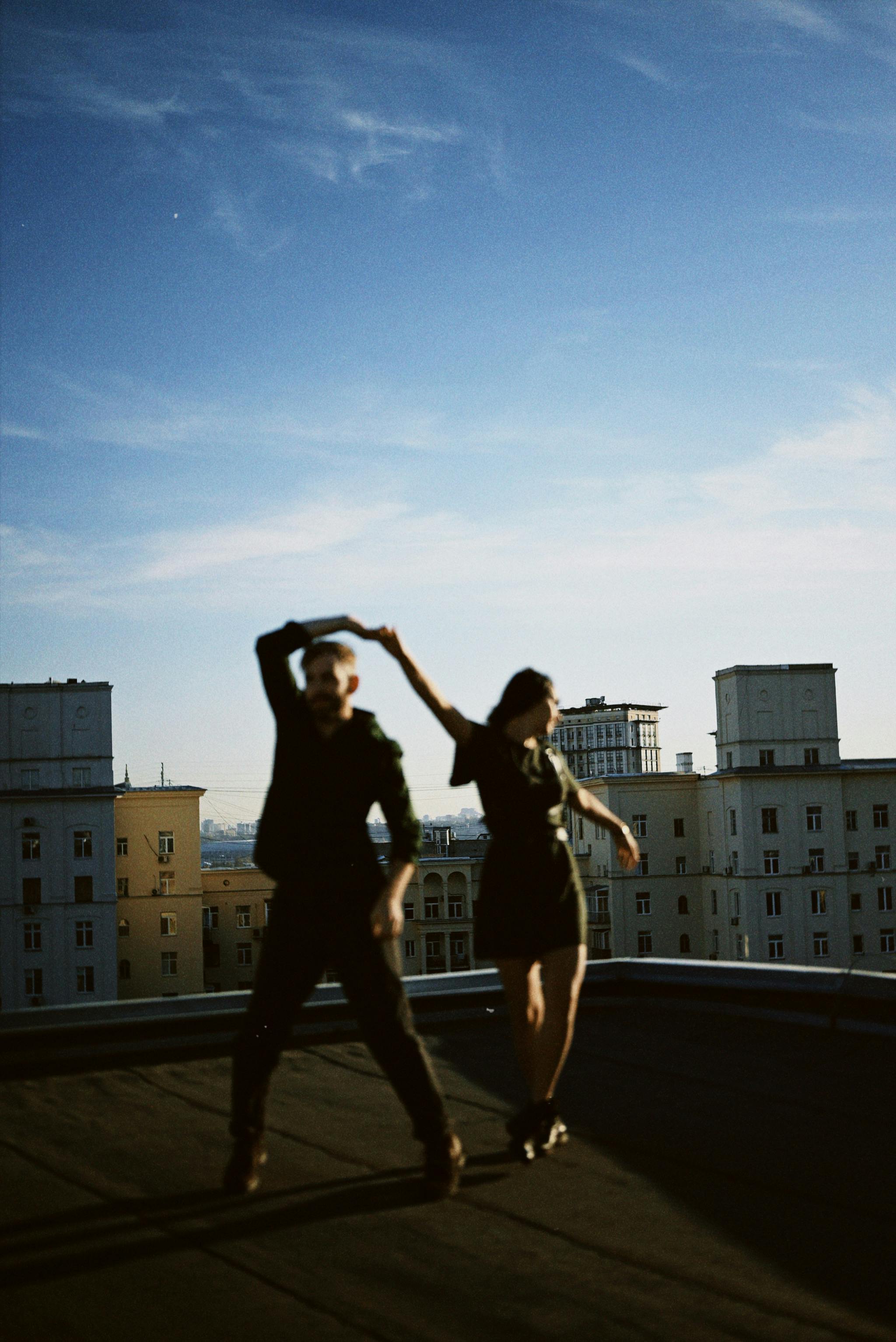 A silhouette of a couple dancing on a city rooftop with a clear sky backdrop.