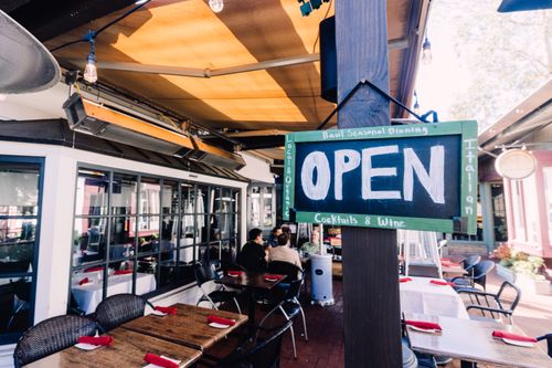 Free Charming outdoor café with open sign, patio seating, and inviting ambiance. Stock Photo