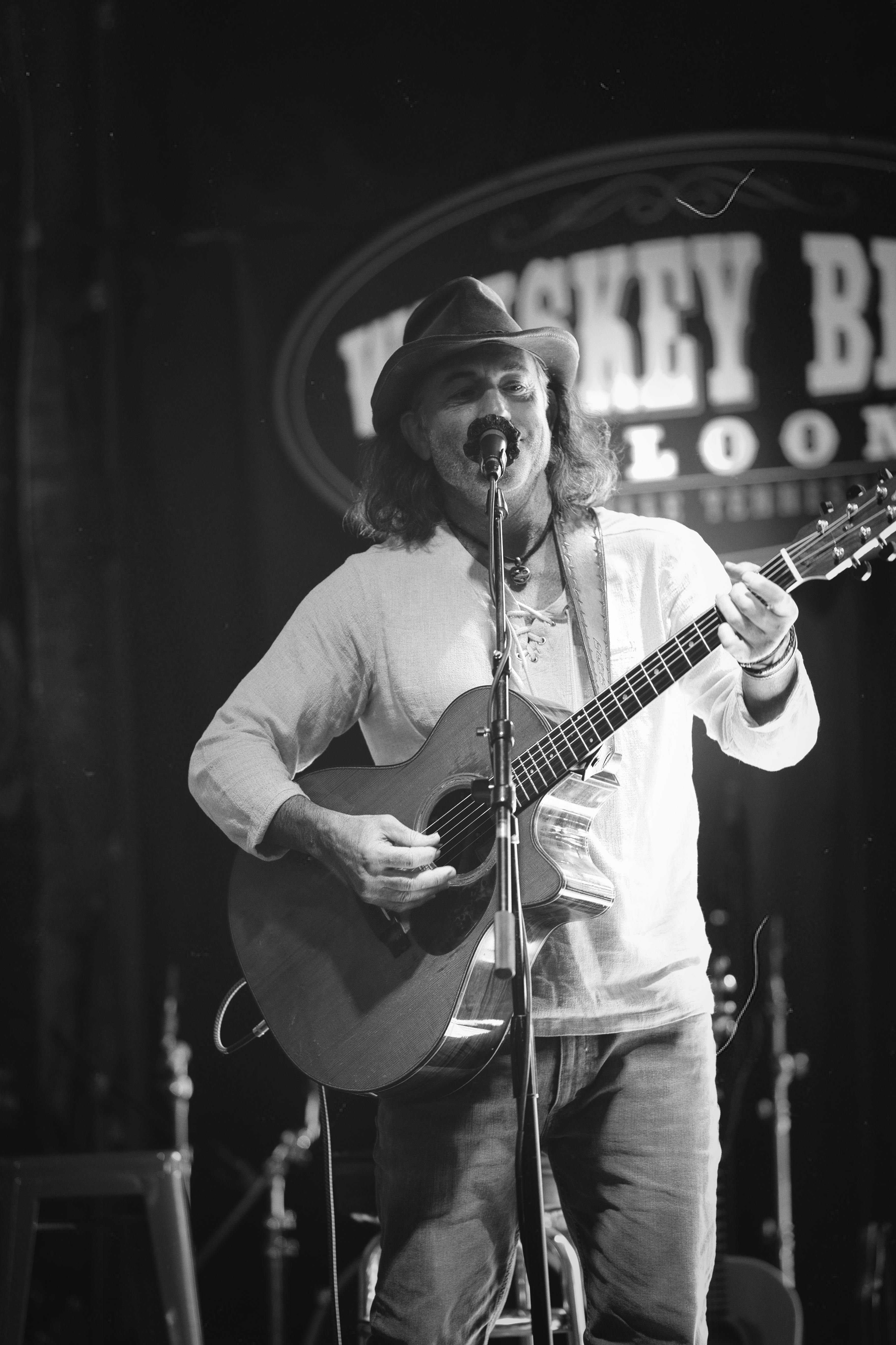 Captivating black and white photo of a musician playing guitar and singing at Whiskey Bent Saloon in Nashville.