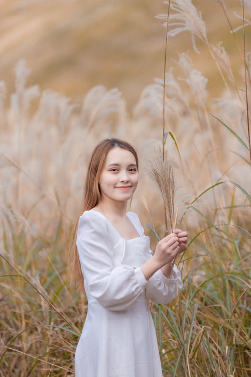 Woman in White Dress Holding Grass