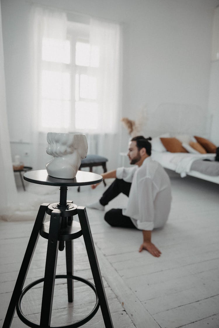 Sculpture On Table And Man Sitting On Floor