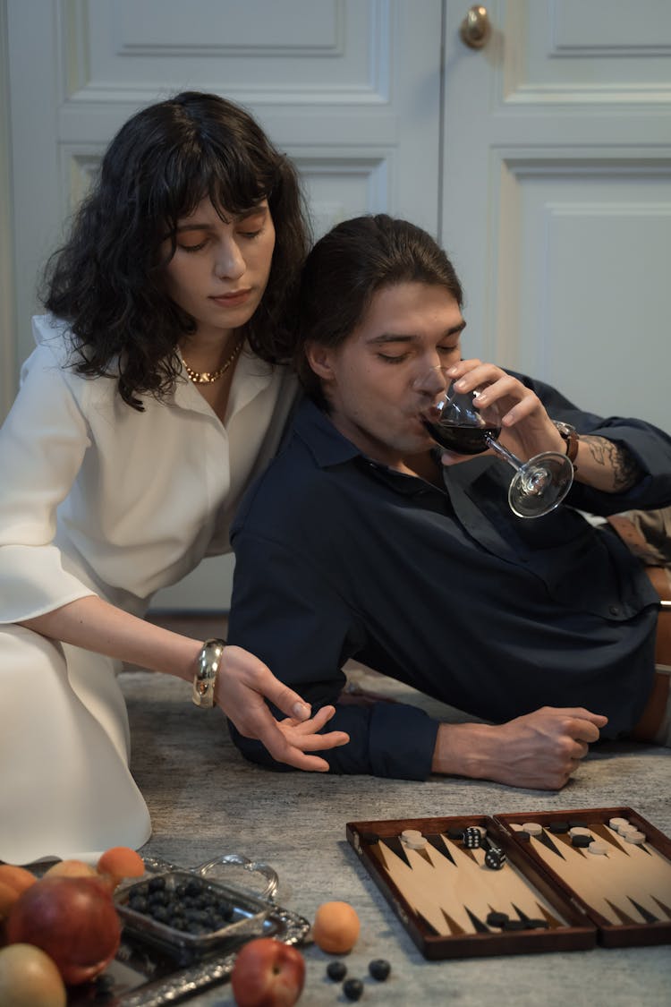 Young Bohemian Couple Doing Home Chilling With Backgammon And Red Wine