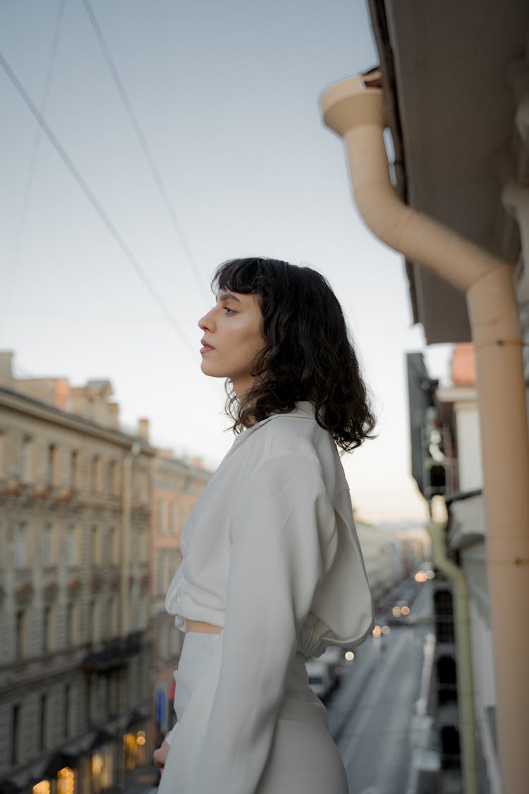 Woman Dressed In White Standing On Balcony