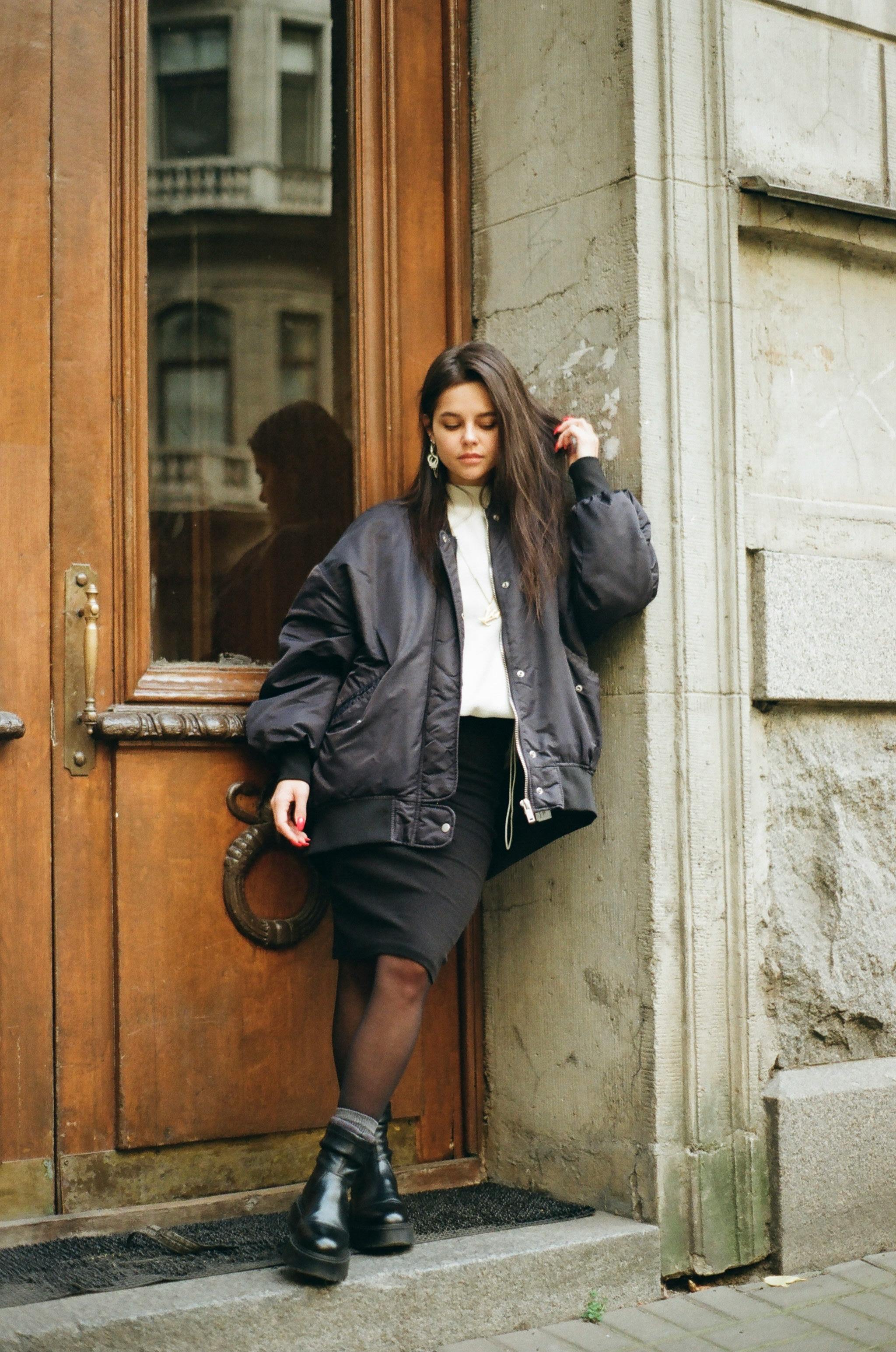 teenage girl standing in door of old building with legs crossed