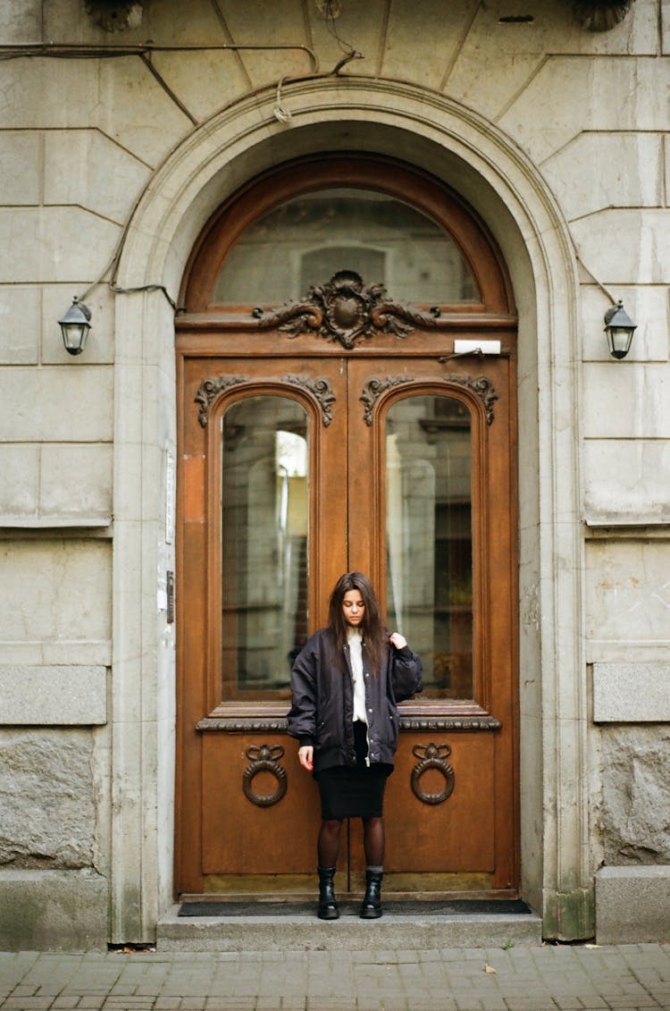 Teenage Girl Standing In Door To Old Building