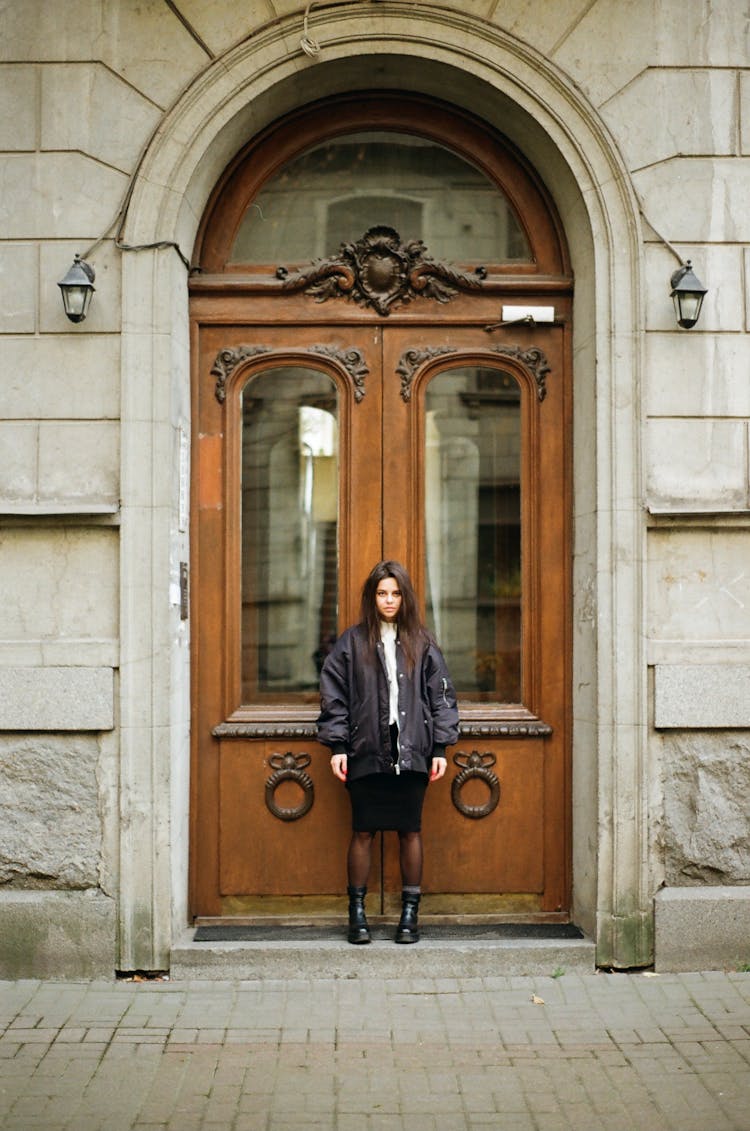 Teenage Girl Standing In Door Of Classic 19th Century Building