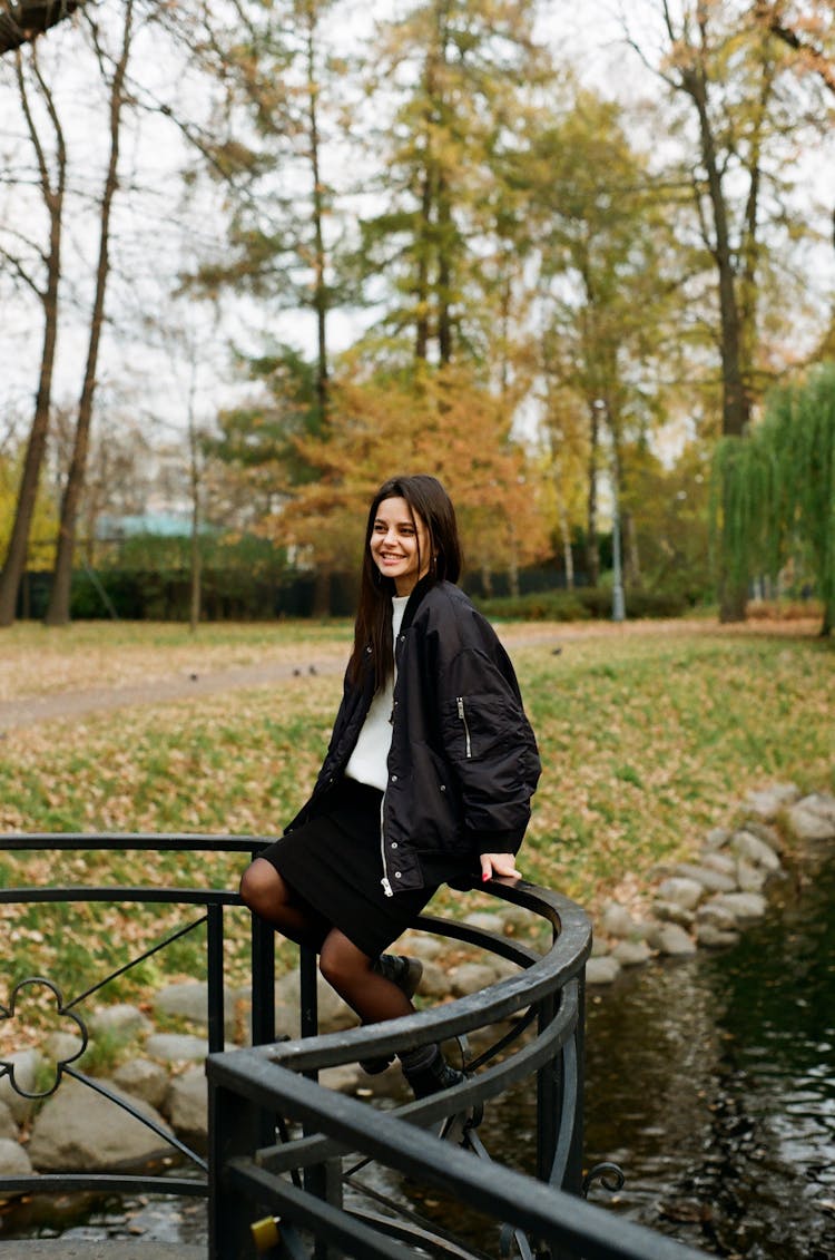 Teenager Wearing School Outfit Sitting On Railing In Park