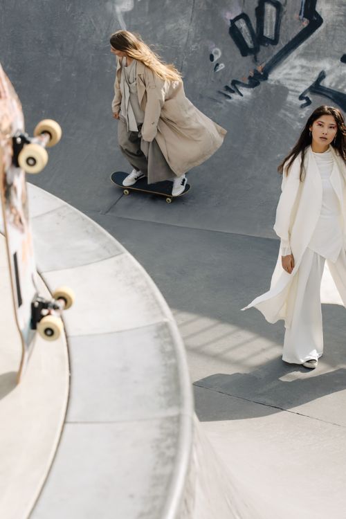 Free Two women showcasing urban fashion while skateboarding in a modern concrete skate park. Stock Photo