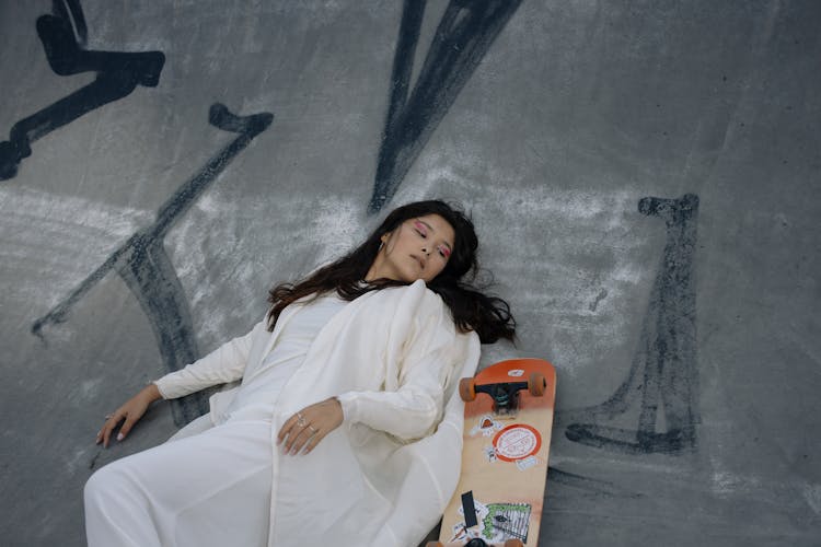 Woman Lying On The Floor Beside A Skateboard