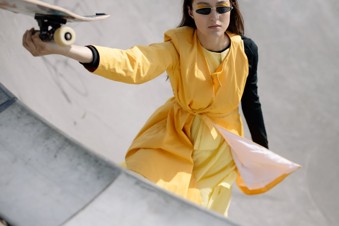 Free A Woman in Yellow Dress Holding A Skateboard Stock Photo