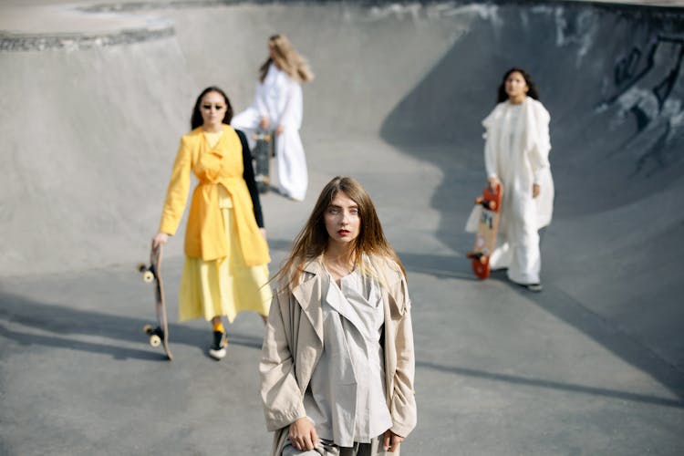 Women Holding Skateboard In Long Dresses Standing On Skate Ramp