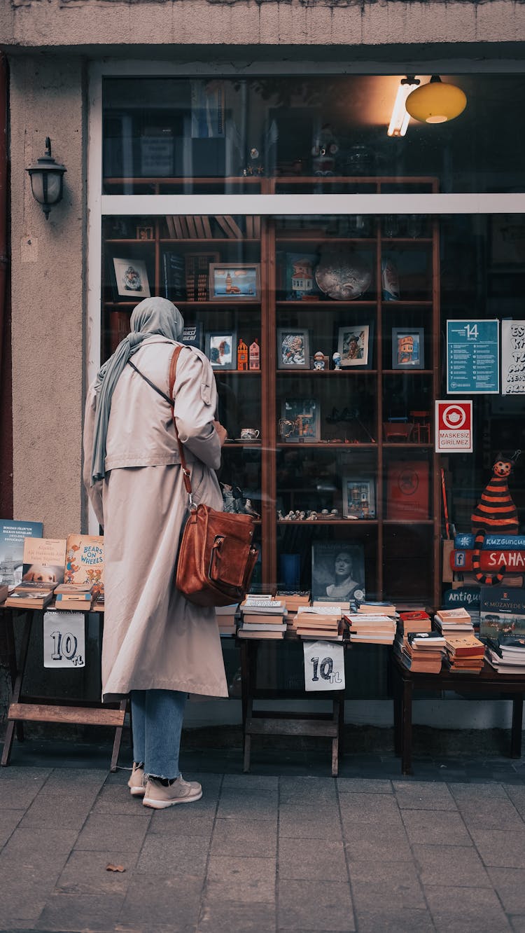 Back View Of A Woman Choosing Books At The Storefront