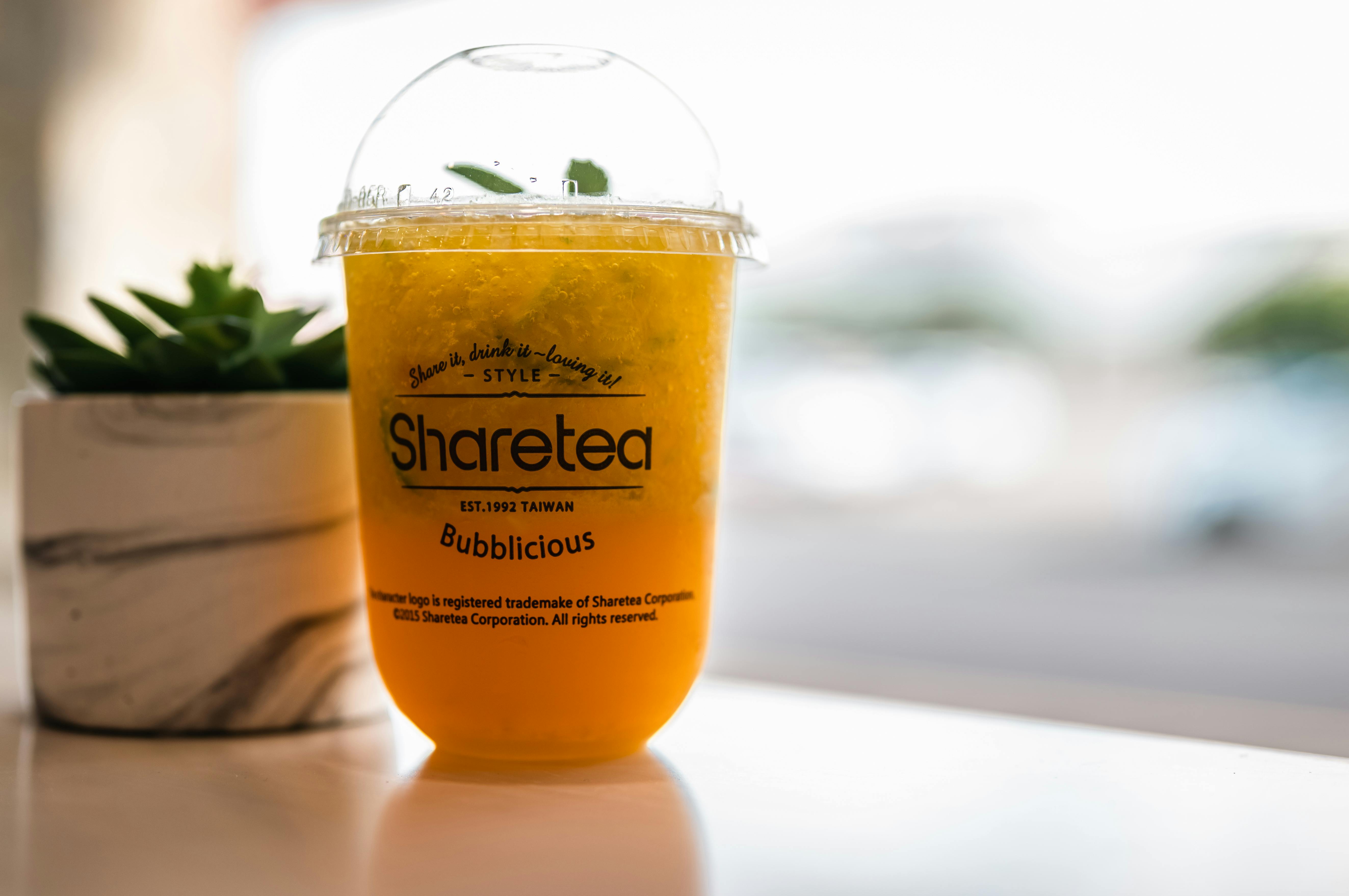 Cold Fruit Tea with a Ice in a Plastic Cup with a Lid on a Wooden