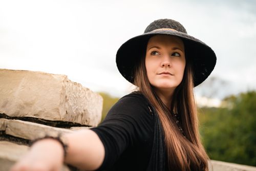 Free Portrait of a woman in a black hat with a serene outdoor backdrop. Stock Photo