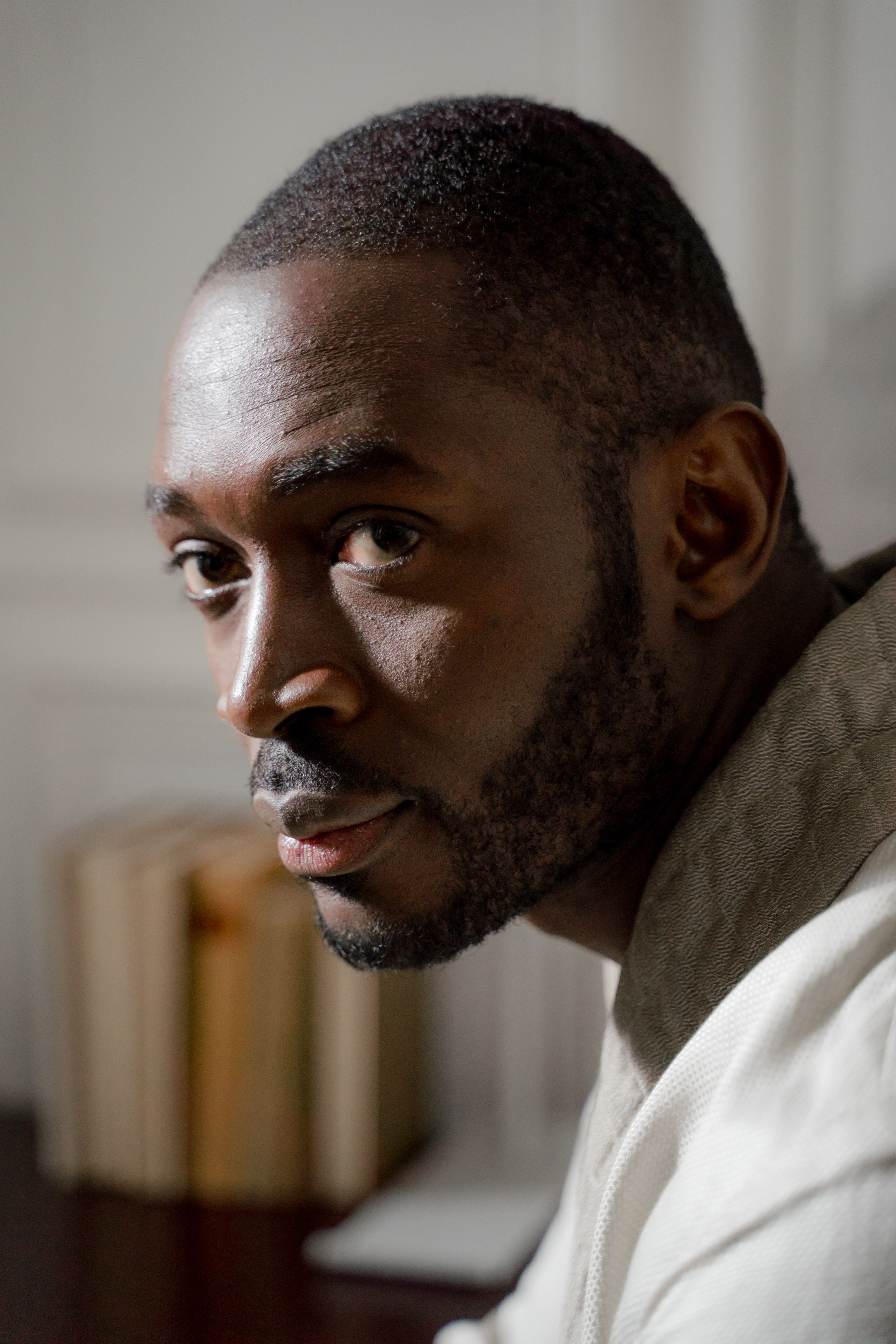 Close-up portrait of a man in a bathrobe with a thoughtful expression indoors.