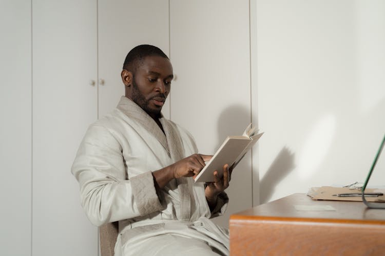 Man In A Bathrobe Sitting While Reading A Book