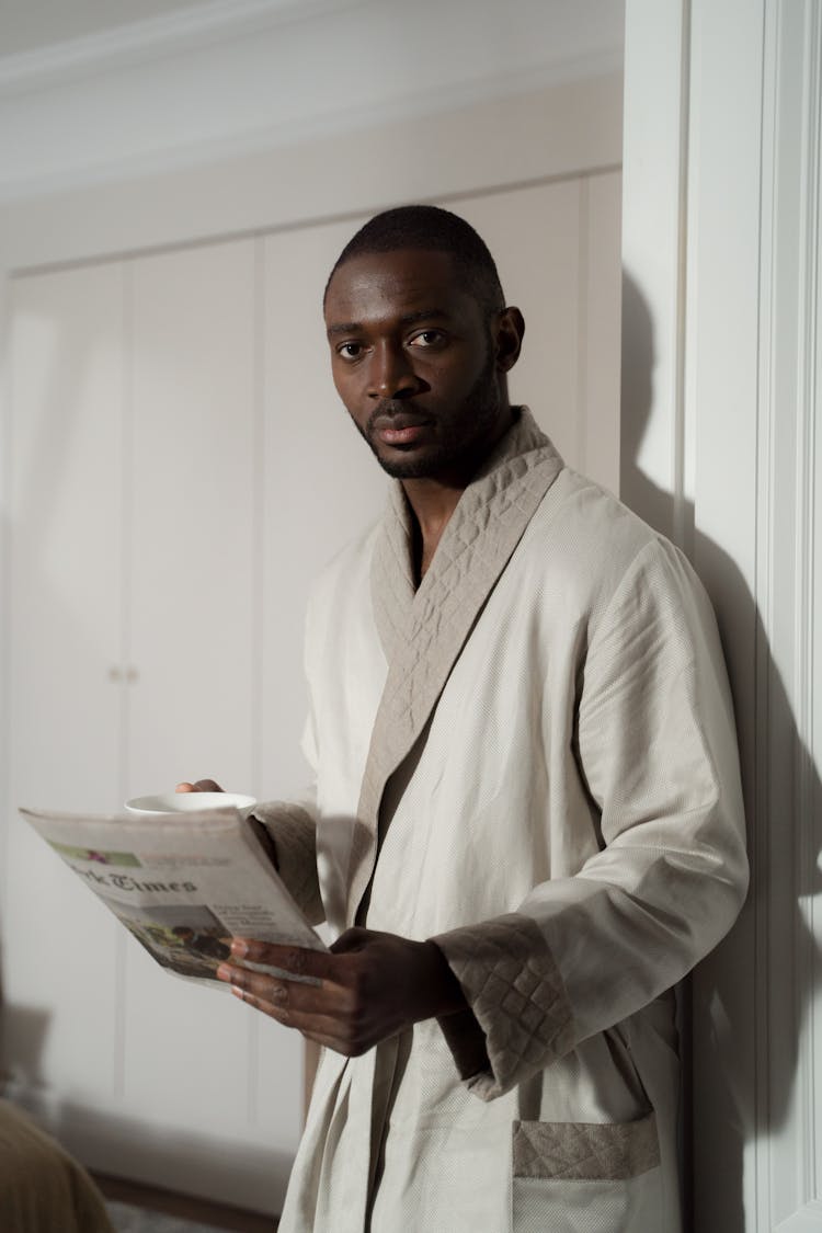 A Man In A Bathrobe Holding A Newspaper