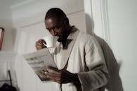 A Man Reading the Newspaper while Drinking Coffee
