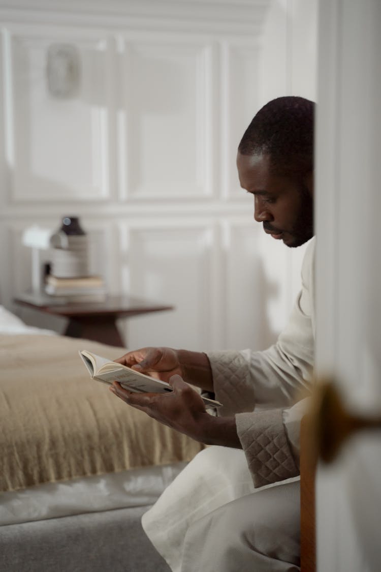 Man In Bathrobe Sitting And Reading In Bedroom