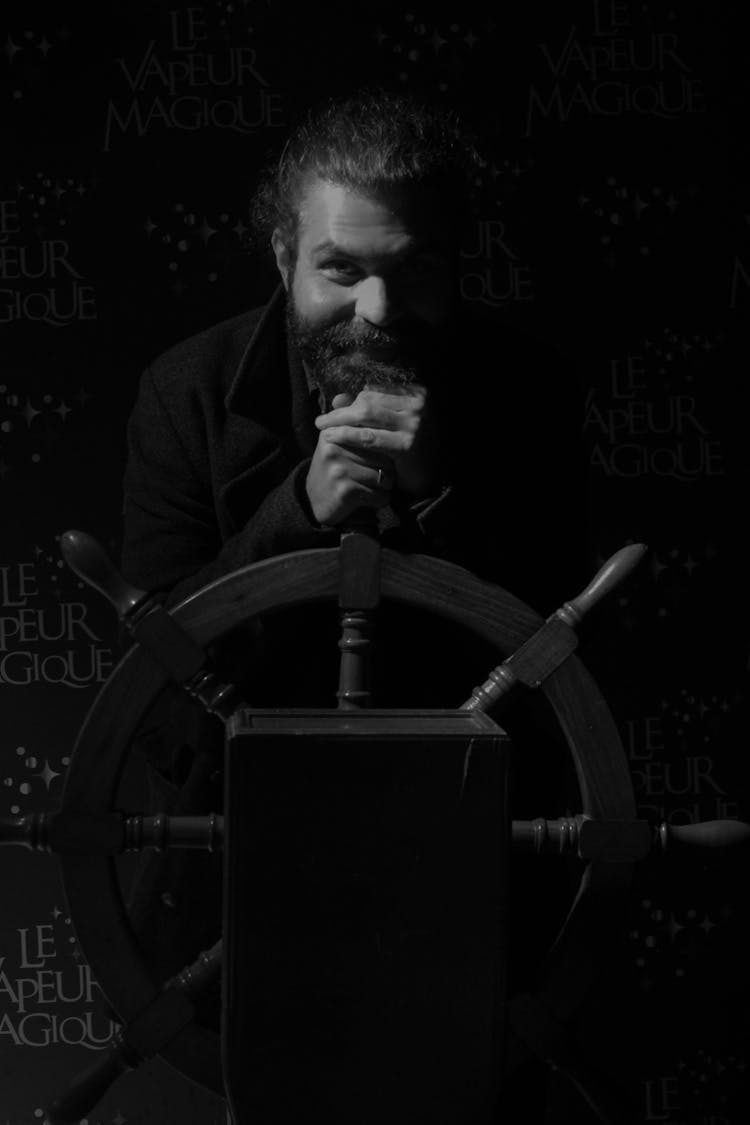 Grayscale Photo Of A Man Holding The Helm