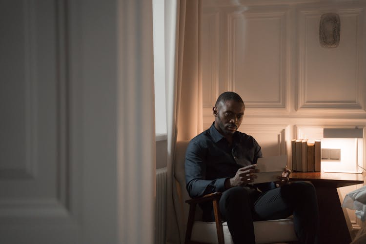 A Man Sitting And Reading A Letter 