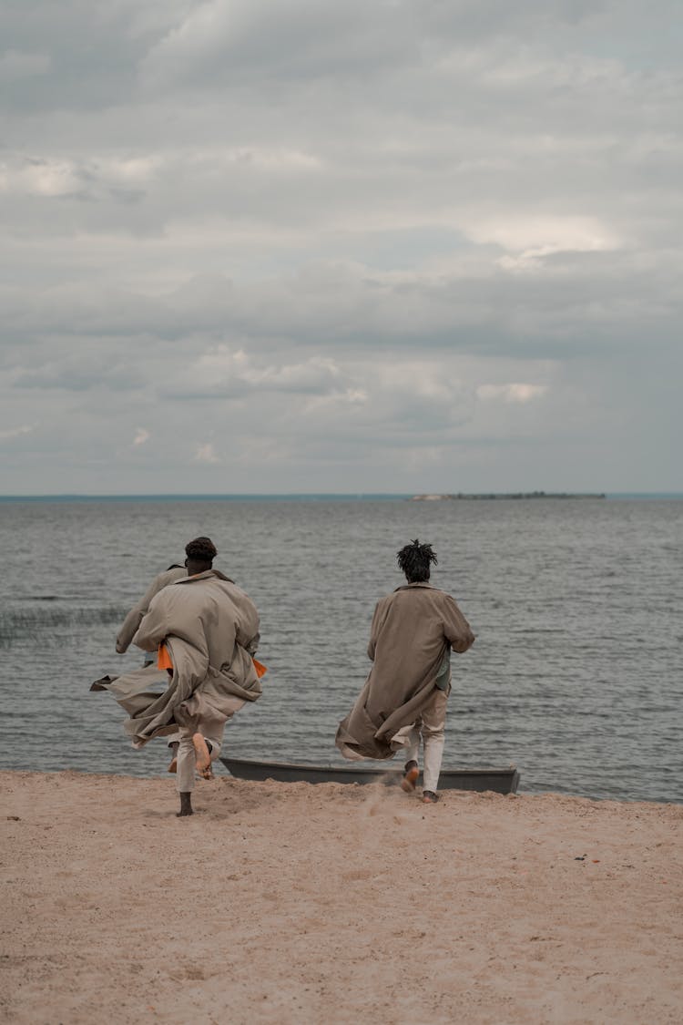 Men In Coats Running Towards Boat On Beach