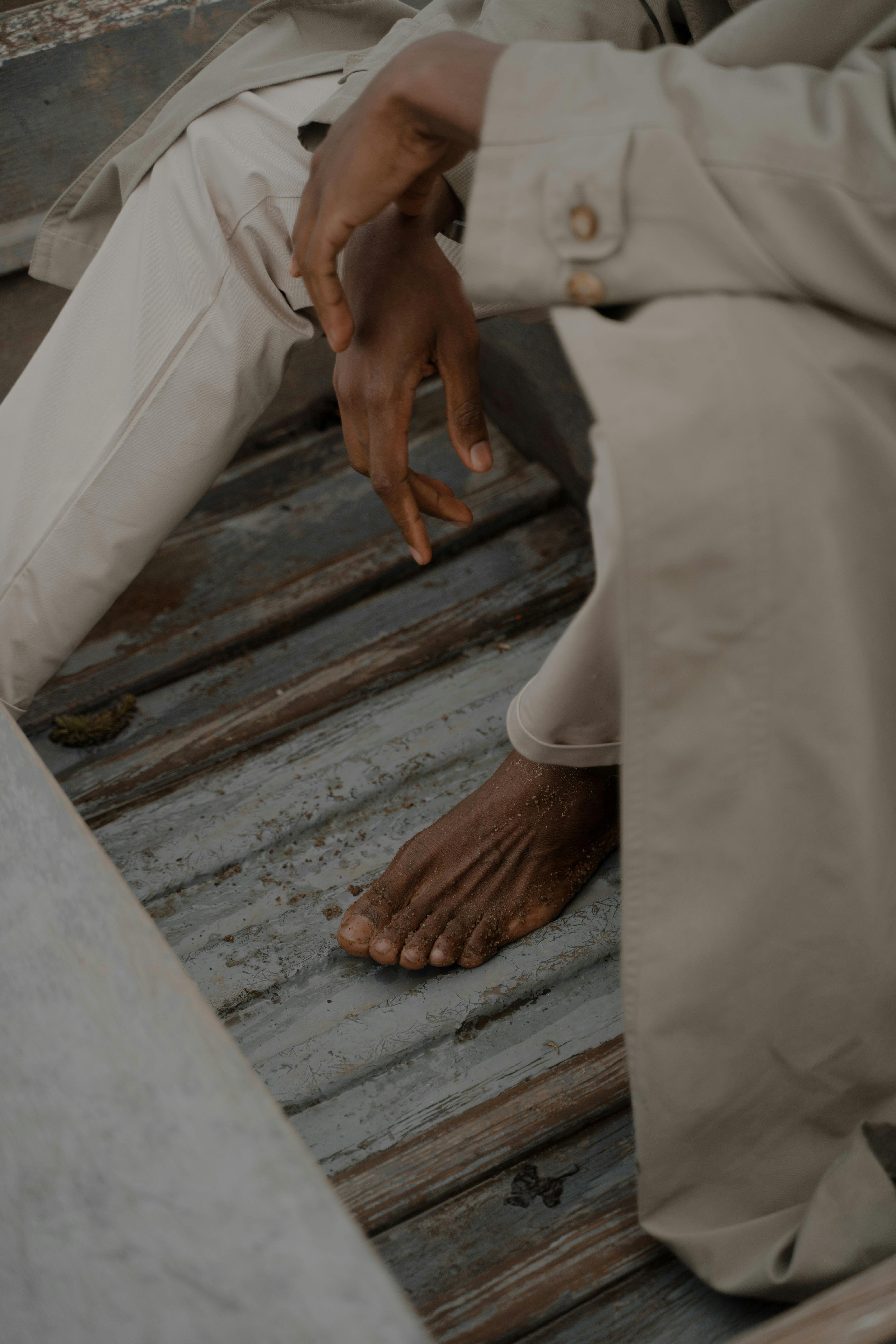 barefoot man in coat sitting in boat