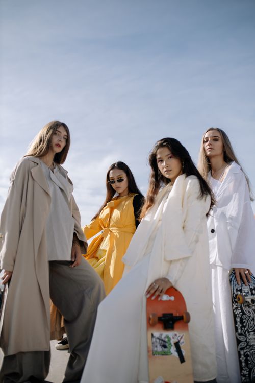 Free Four fashionable women pose confidently with skateboards under a bright sky. Stock Photo