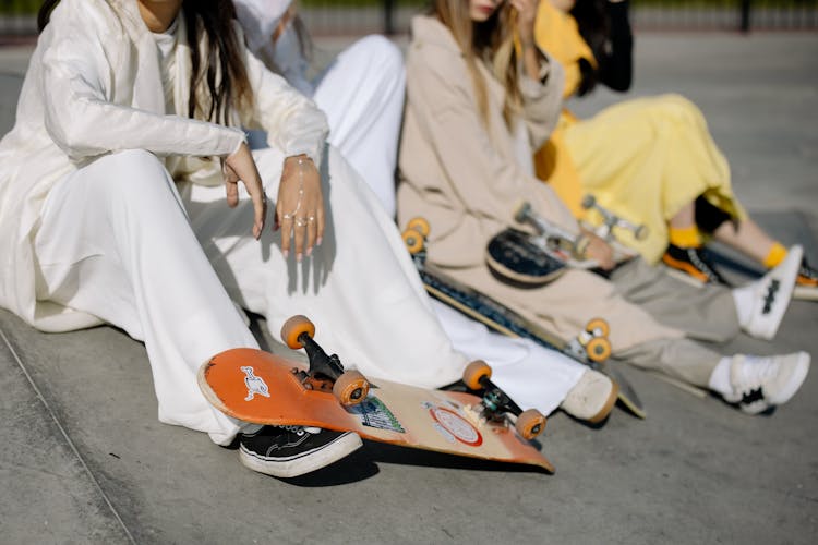 People In Long Sleeve Clothes Sitting On Concrete Ground With Skateboards