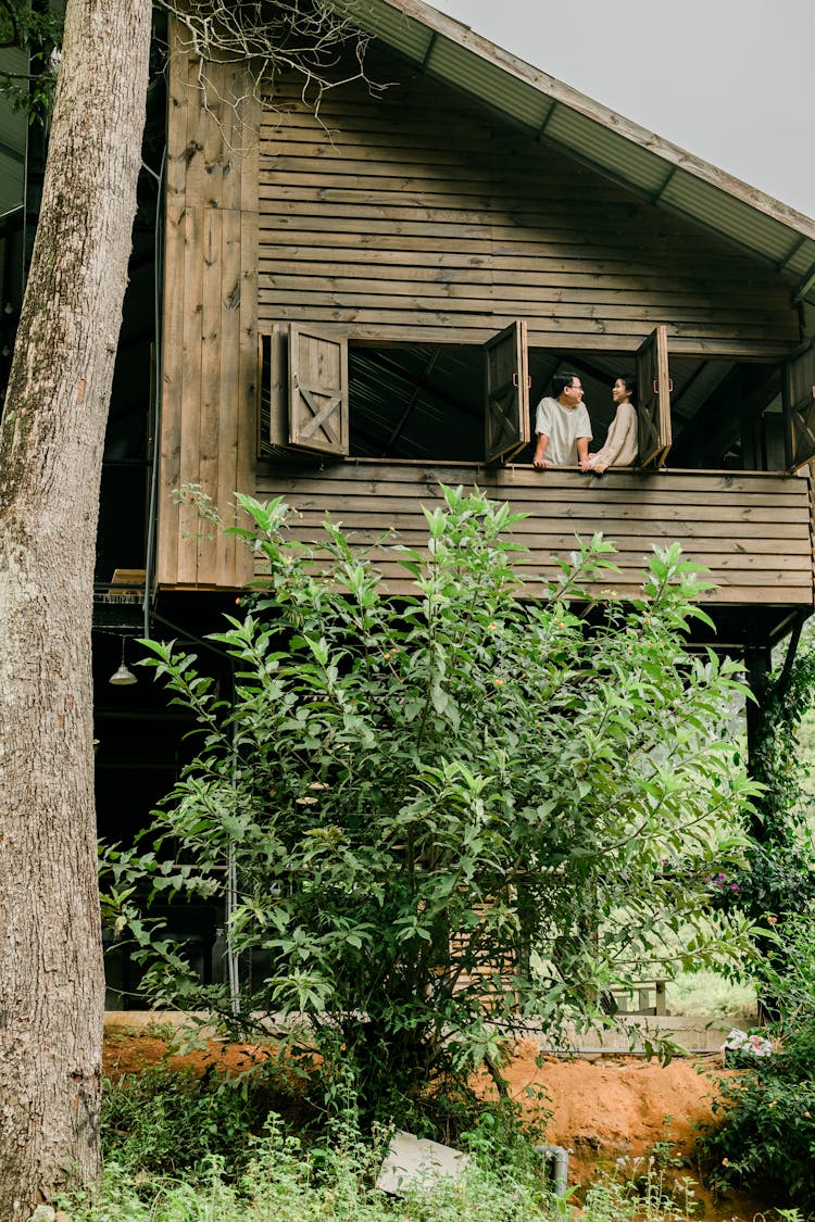 Couple In Window Of Wooden House