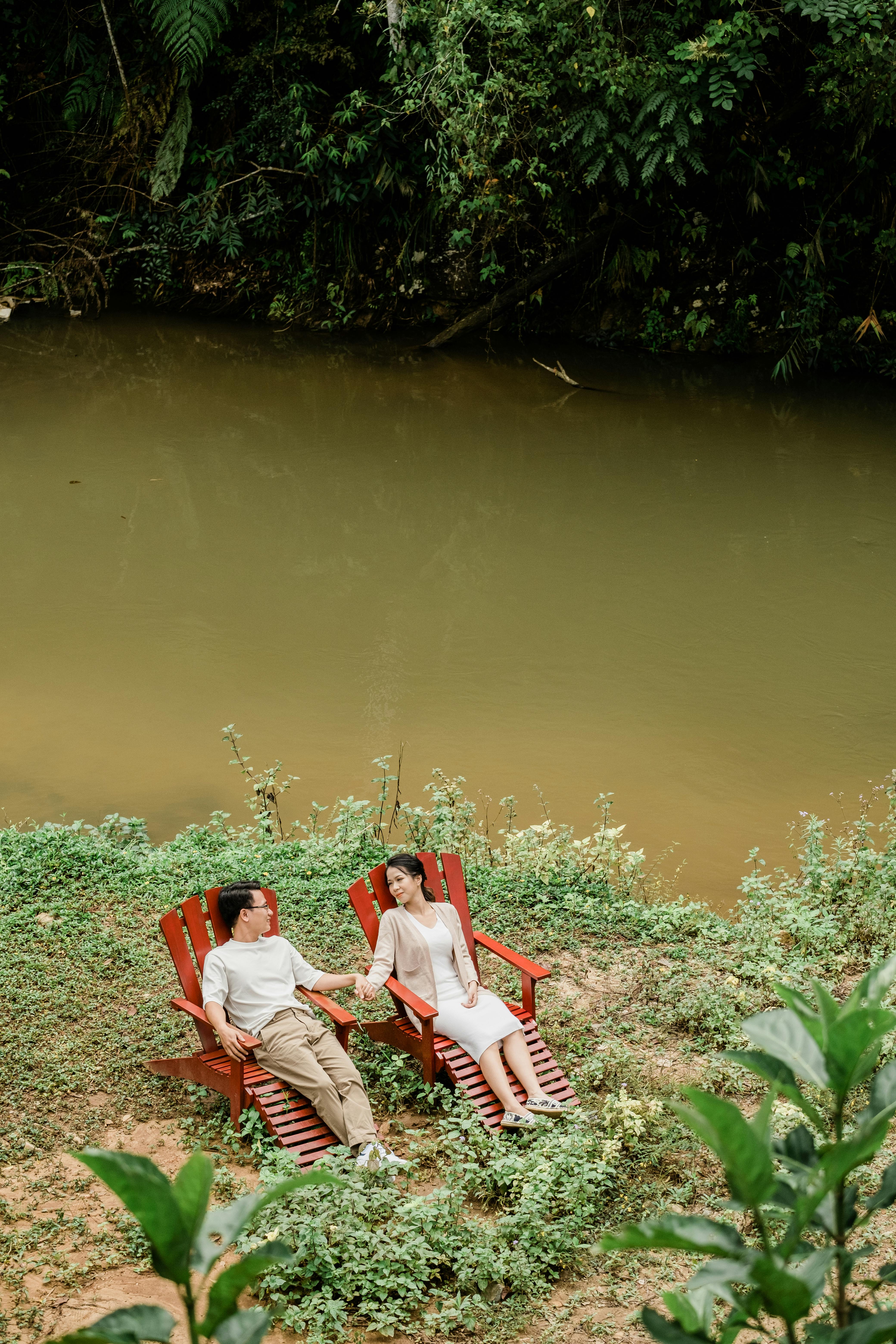 A serene scene of a couple resting outdoors by a riverside, enjoying nature.