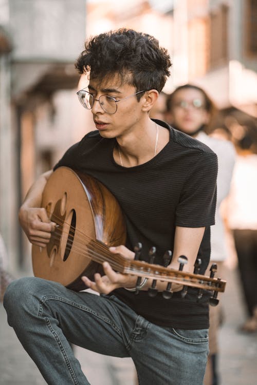 Man in Black Shirt Playing Brown Acoustic Guitar on Street Sidewalk