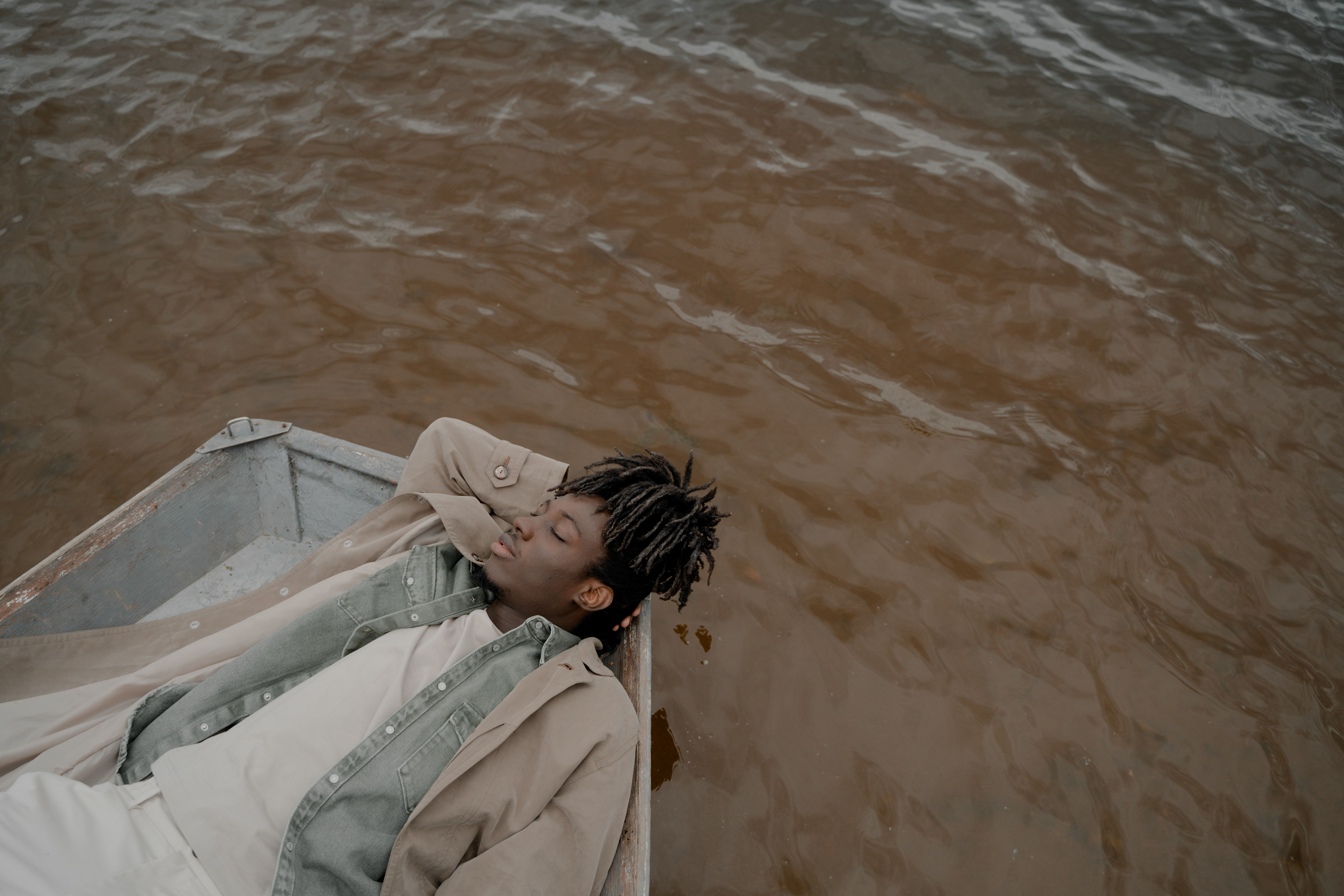 Serene image of a man relaxing in a boat, floating on calm waters.