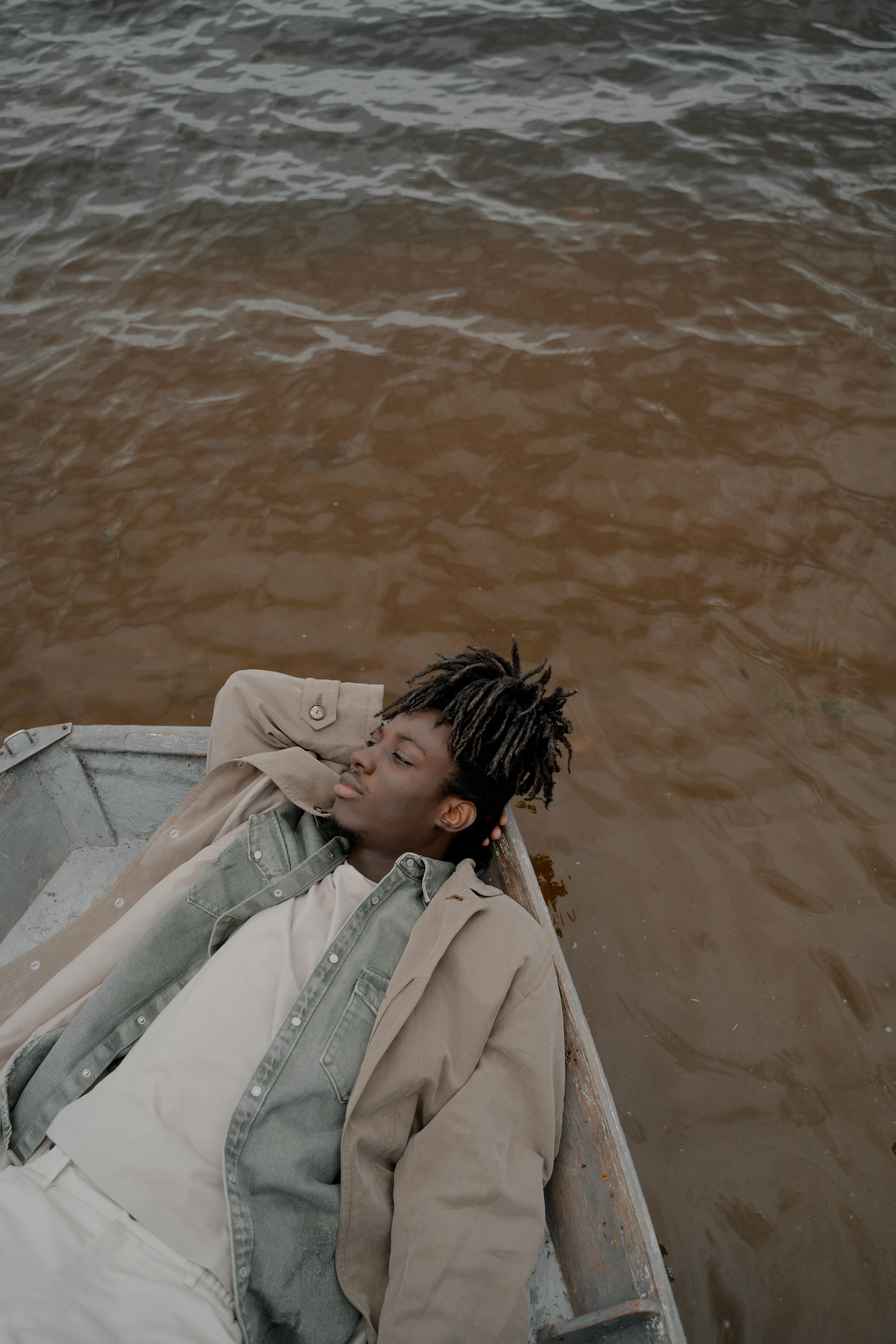 A serene moment of relaxation for a man lying on a boat, enjoying the tranquil lakeside view.