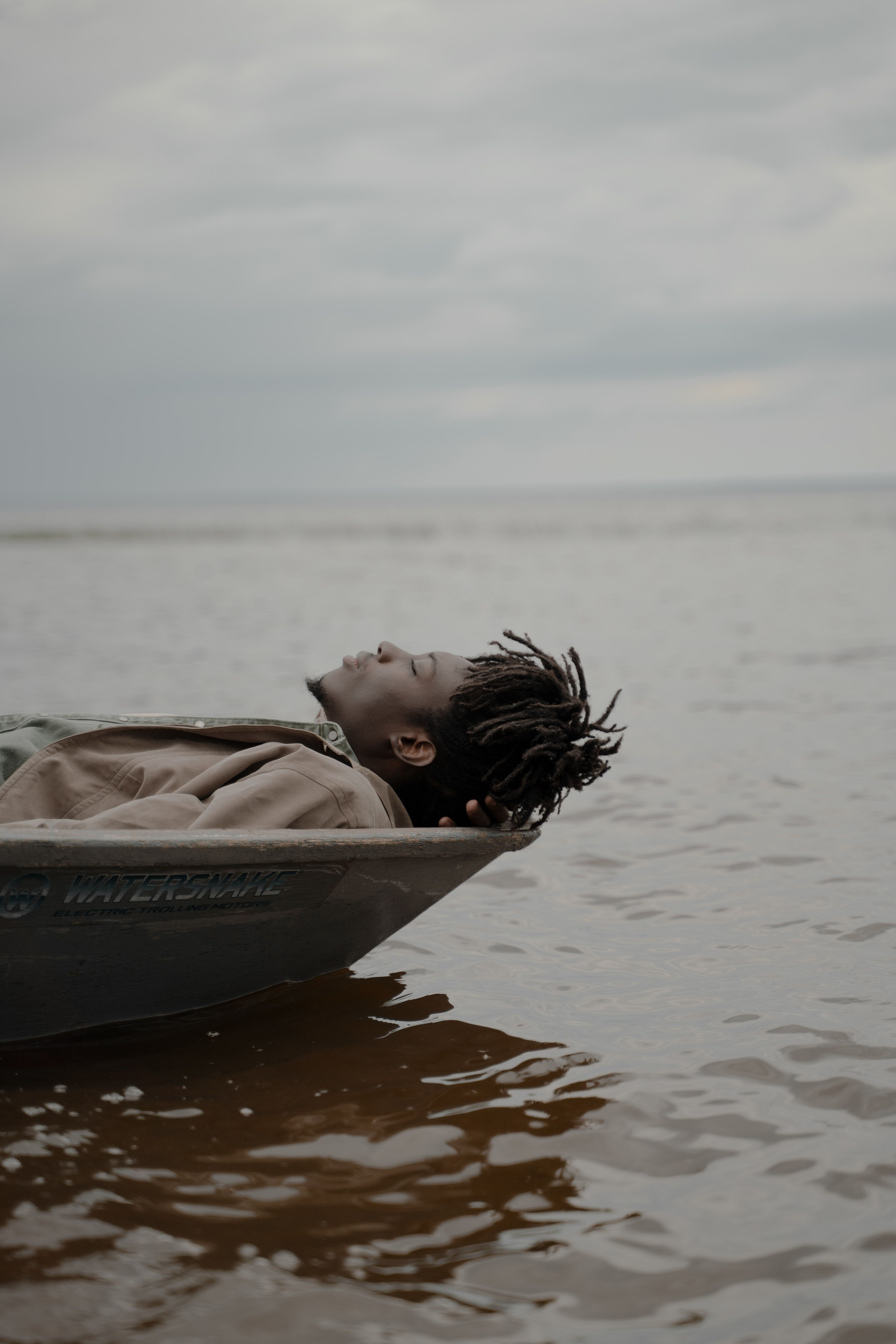 Man relaxes on a boat in tranquil sea, eyes closed, enjoying serene moments.