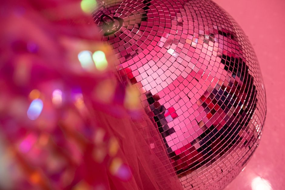 Close-up of a disco ball reflecting pink lights, creating a lively party atmosphere.