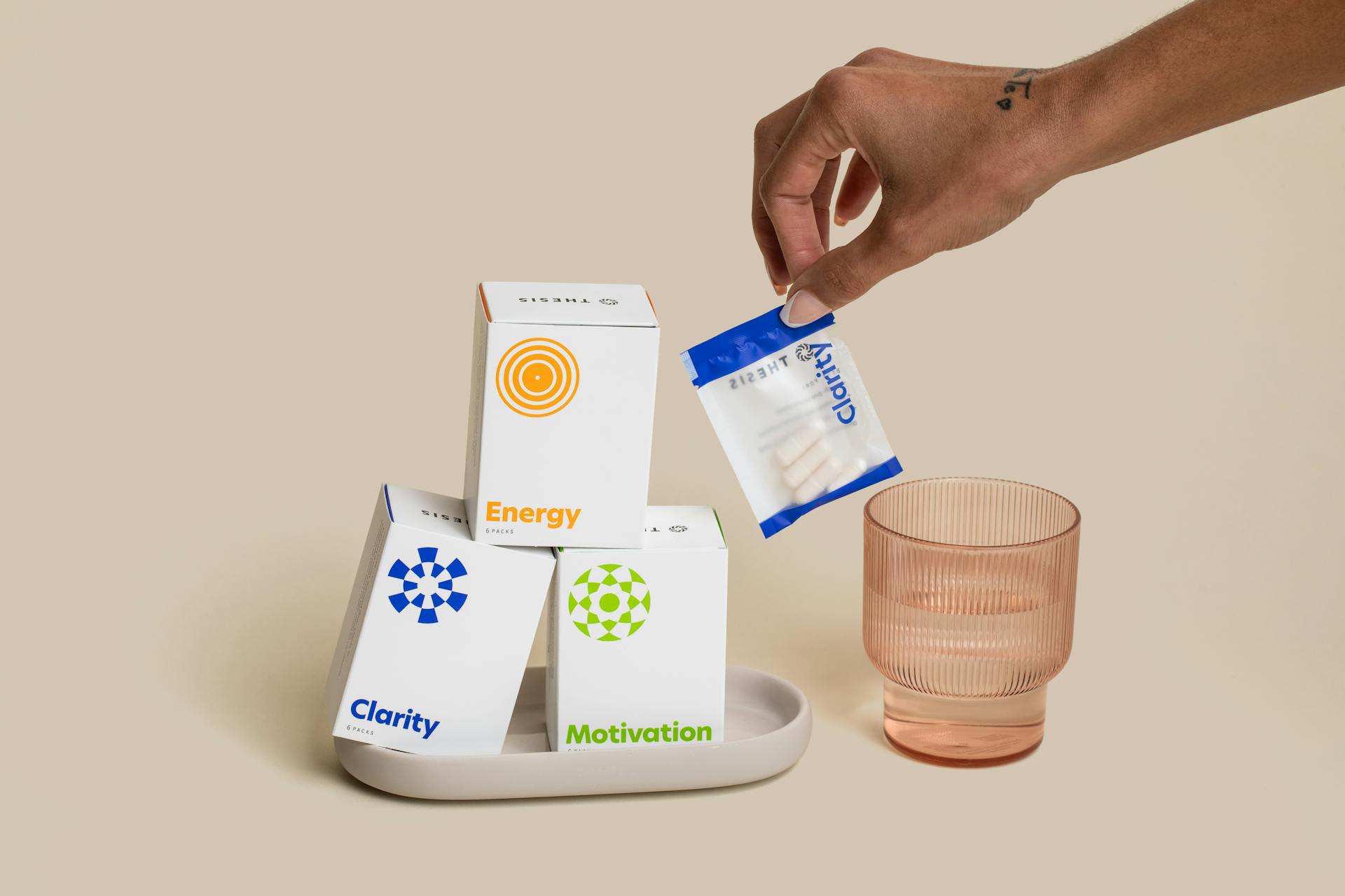 A close-up of dietary supplements for clarity, motivation, and energy with packaging and a hand reaching for a pouch.
