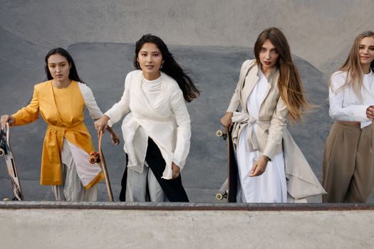 Four stylish women with skateboards in a skate park, exuding modern fashion and togetherness.