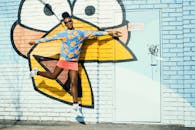 一名年轻女子在充满活力的卡通涂鸦墙前快乐地跳跃