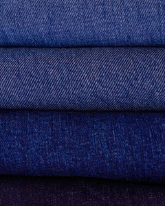 Close-up of neatly stacked folded denim fabrics in varying blue tones showcasing texture and pattern.