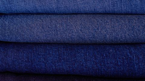 Close-up of neatly stacked folded denim fabrics in varying blue tones showcasing texture and pattern.