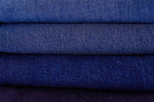 Close-up of neatly stacked folded denim fabrics in varying blue tones showcasing texture and pattern.