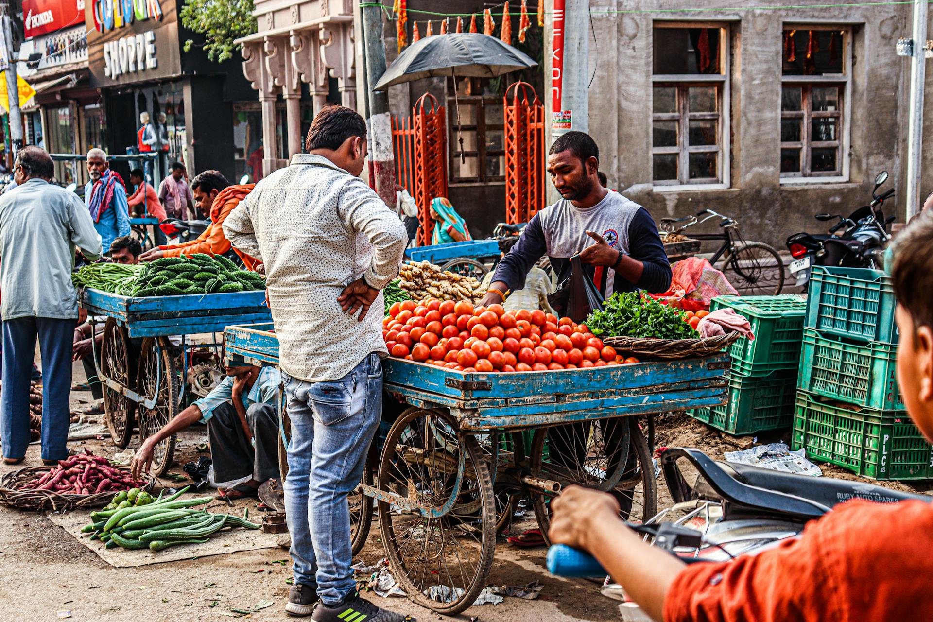 Bustling street market with vendors selling fresh fruits and vegetables outdoors.