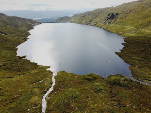 A Lake Surrounded by Green Grass Covered Mountain 