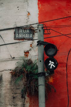 Traffic light on Rua Anhaia with urban decay and vibrant red wall.