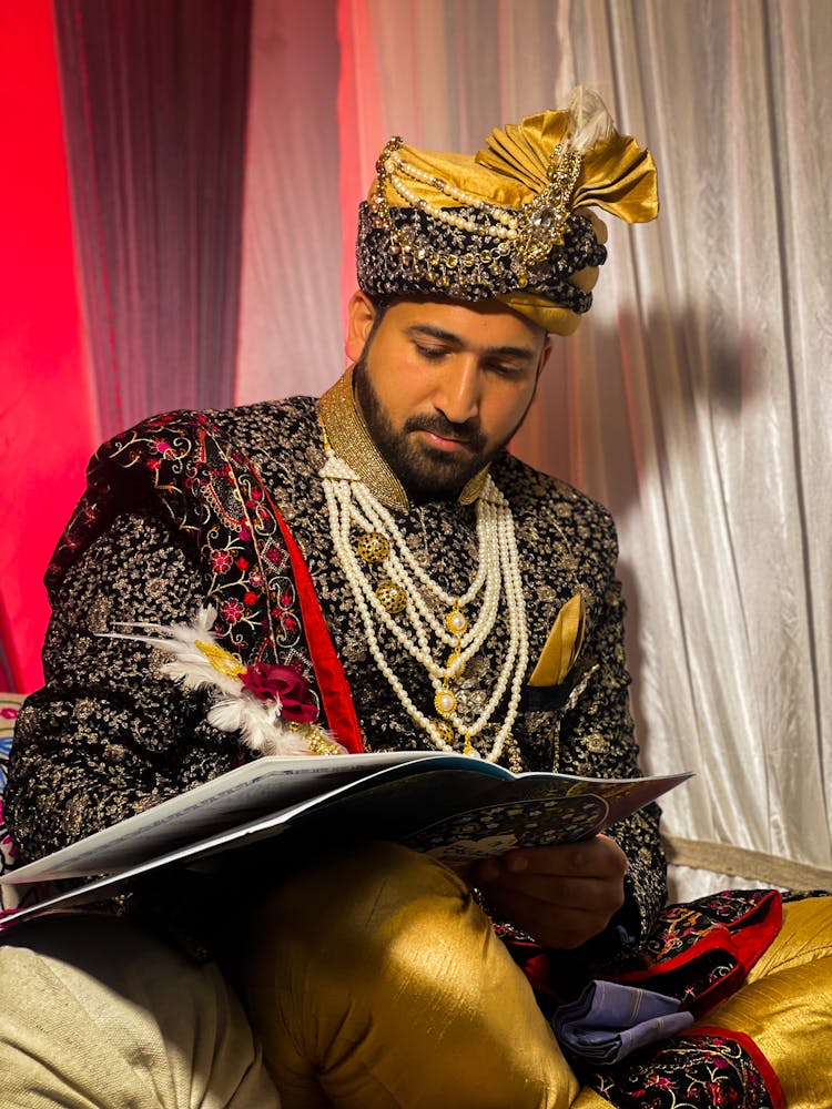 Groom Sitting In Traditional Wedding Clothes Holding And Writing On A Notebook