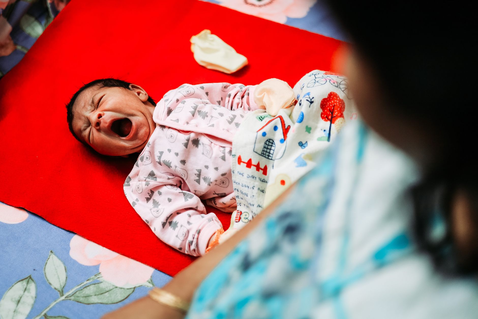 A yawning baby lies on a vibrant bedspread, showcasing cute sleepwear and a cozy atmosphere.