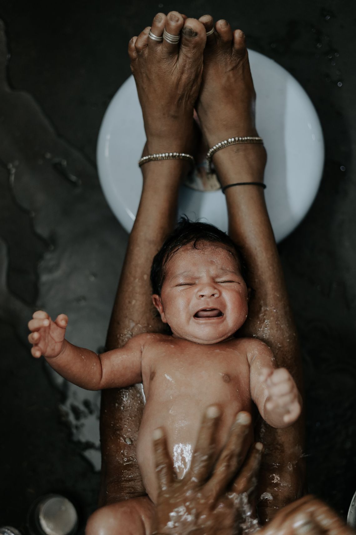 Newborn baby receiving a gentle bath with careful hands